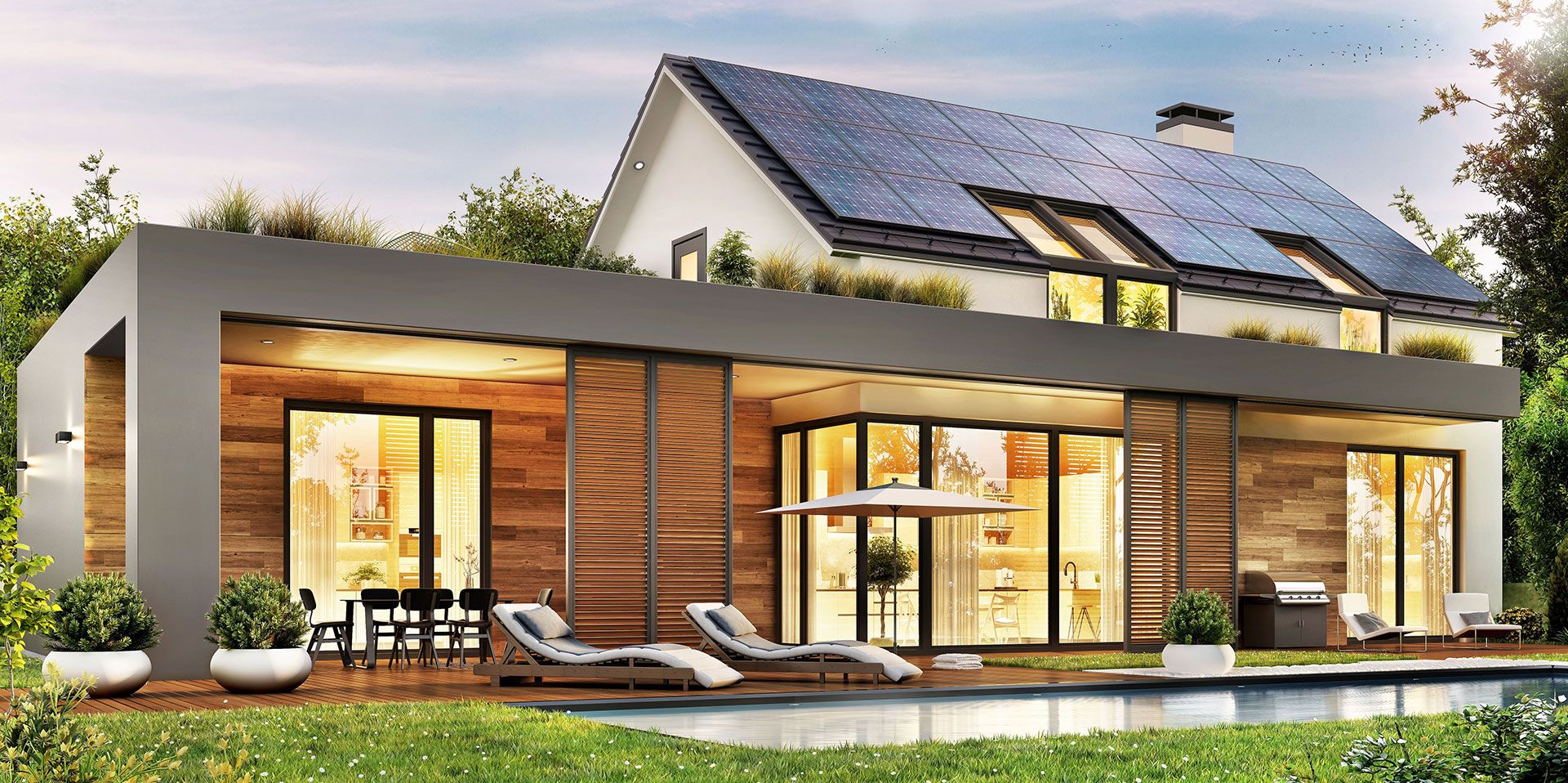 Vom Garten ausgehende Ansicht eines Hauses mit Solarmodulen auf dem Dach und einem Vorbau mit flachem Dach, innen beleuchtet, mit Pool und gemütlichen Liegen auf der Terrasse